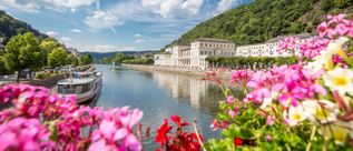 Blick auf die Lahn in Bad Ems mit Ausflugsschiff, Uferpromenade und historischen Gebäuden vor bewaldeten Hängen