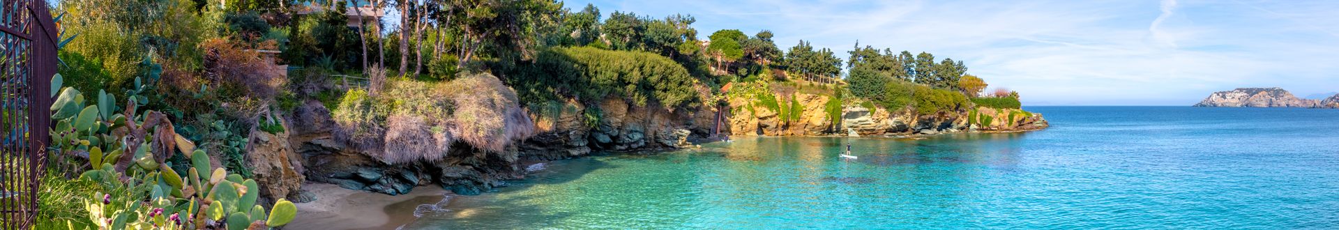 Kleiner Sandstrand mit klarem türkisfarbenem Wasser und bewachsenen Felsen auf Kreta