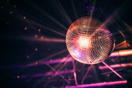 Leuchtende Discokugel an der Decke eines Clubs, reflektiert buntes Licht im Raum