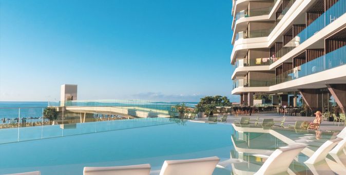 Infinity-Pool mit Liegestühlen auf der Terrasse eines modernen Hotels mit Meerblick