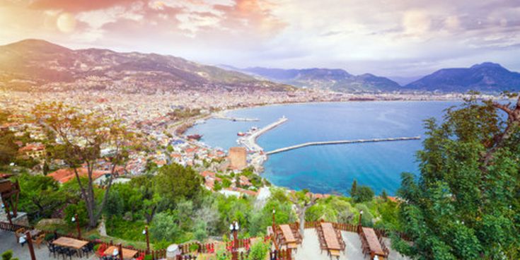Panorama von Alanya mit Blick auf den Hafen, den roten Turm und die weitläufige Stadtlandschaft vor der Bergkulisse