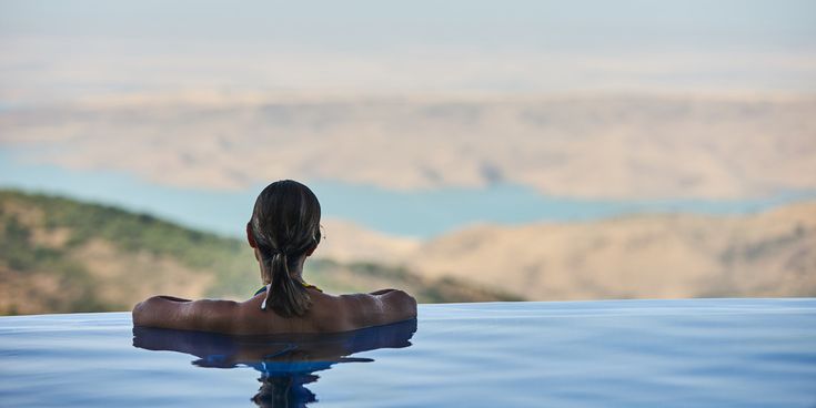 Person entspannt in einem Infinity-Pool mit Blick auf das offene Meer