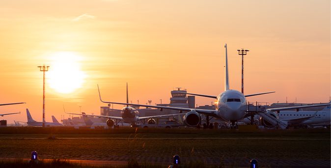 Flugzeuge auf dem Rollfeld des Düsseldorfer Flughafens bei Sonnenuntergang mit Kontrollturm im Hintergrund