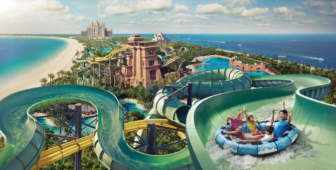 Familie auf Wasserreifen in einer großen Wasserrutsche des Wasserparks des Atlantis, The Palm in Dubai mit Blick auf Strand, Meer und Resort