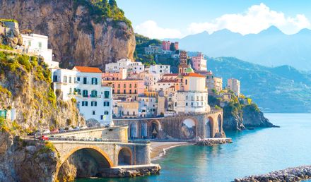 Blick auf die italienische Amalfi-Küste mit bunten Häusern und historischen Gebäuden an steilen Felsen über dem Mittelmeer