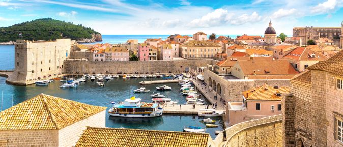 Panoramablick auf die historische Altstadt von Dubrovnik in Kroatien mit Hafen, Stadtmauern, Booten und den charakteristischen Terrakottadächern an der Adriaküste