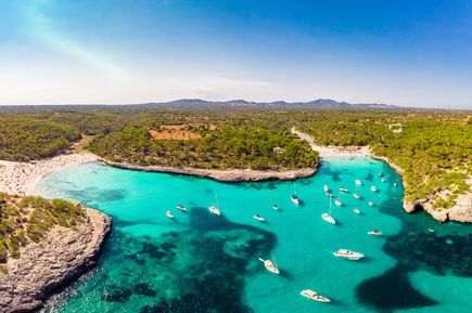 Luftaufnahme der Cala Mondragó auf Mallorca mit türkisblauem Wasser, Sandstränden und zahlreichen Booten in der Bucht