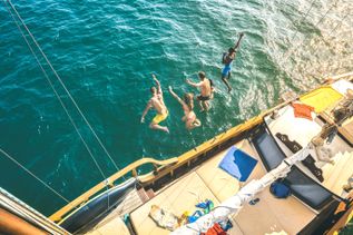 Mehrere Personen springen vom Katamaran ins Meer