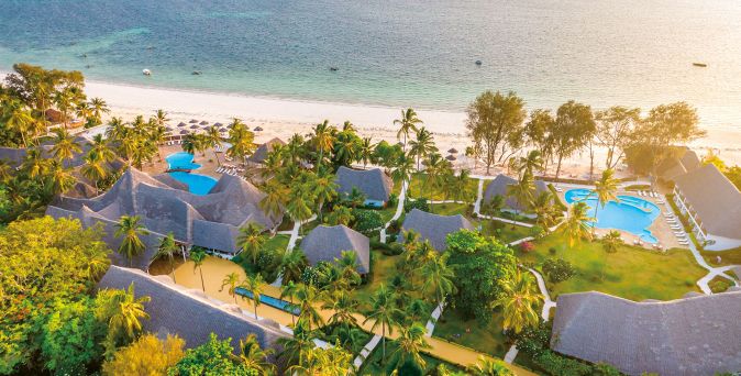 Luftaufnahme des Kiwengwa Beach Resort auf Sansibar mit tropischer Gartenanlage, mehreren Pools, strohgedeckten Gebäuden, Palmen und weißem Sandstrand am Indischen Ozean
