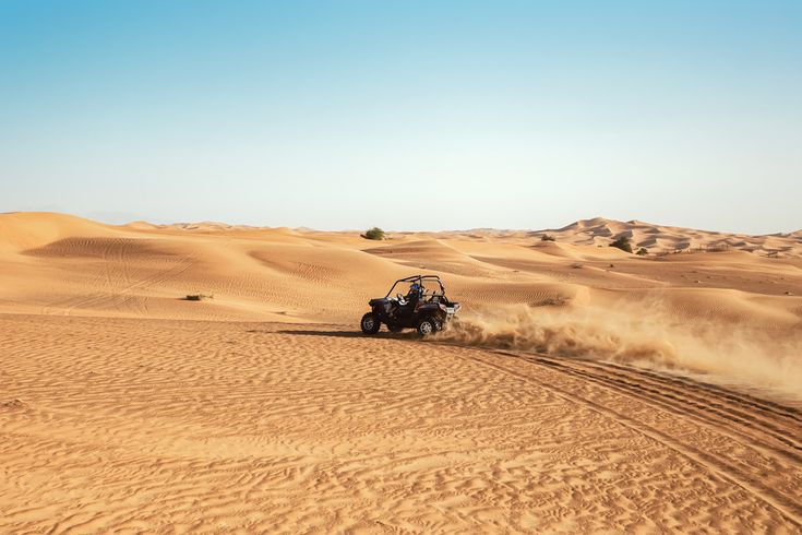 Buggy fährt mit hoher Geschwindigkeit durch Sanddünen in der Wüste