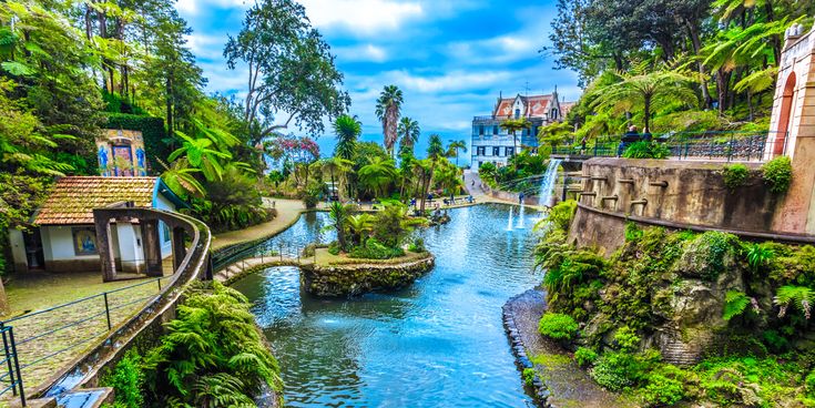 Tropischer Garten Monte Palace auf Madeira mit Teichen, Wasserfontänen, üppiger Vegetation, Farnen, Palmen und verschlungenen Spazierwegen