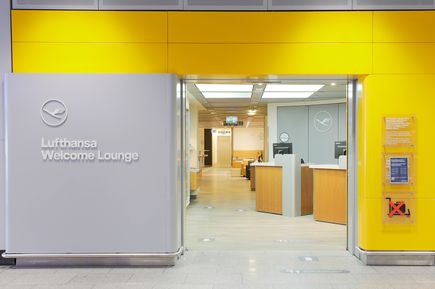 Eingang zur Lufthansa Welcome Lounge am Flughafen Frankfurt mit gelber Fassadengestaltung, Empfangsbereich und sichtbarem Lufthansa-Logo