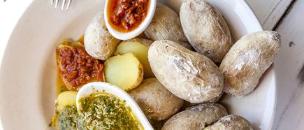 Teller mit mehreren kleinen Kartoffeln und zwei Löffeln mit grüner und roter Sauce