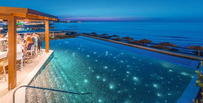 Abendstimmung im Hotel Cactus Mare mit beleuchtetem Pool direkt am Meer, umgeben von Liegestühlen und einem offenen Restaurantbereich