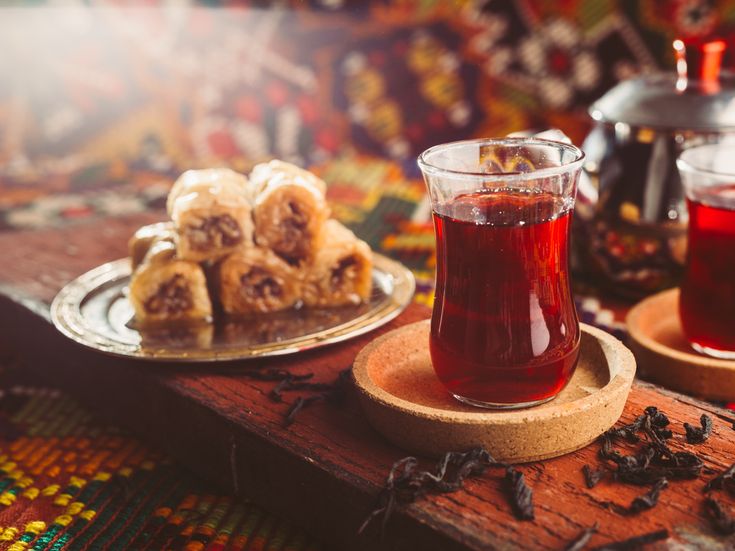 Traditionelles Glas Tee mit einem Teller Baklava auf einem Holztisch im orientalischen Ambiente