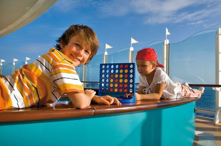 Zwei Jungen spielen eine Runde Vier gewinnt auf dem Außendeck der AIDAbella, mit Blick auf das Meer und blauem Himmel im Hintergrund