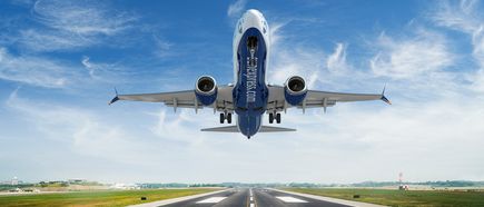 SunExpress Boeing 737-8 im Landeanflug über einer Start- und Landebahn mit ausgefahrenem Fahrwerk vor blauem Himmel