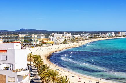 Weitläufiger Blick auf den Strand von Can Pastilla auf Mallorca mit türkisblauem Meer, Hotels, Palmen und einer lebhaften Promenade
