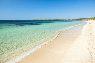 Weitläufiger Sandstrand Playa de Migjorn auf Formentera mit klarem, türkisblauem Wasser und ruhiger Küstenlinie