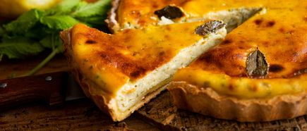 Traditioneller ibizenkischer Flaó-Kuchen mit Käse und Minze, frisch angeschnitten auf rustikalem Holztisch