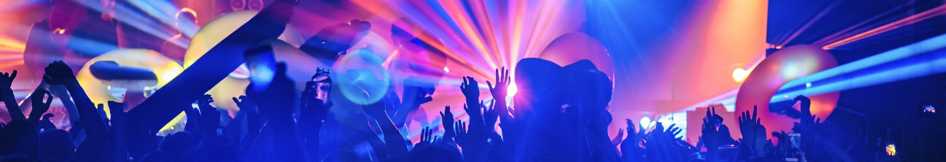 Menschenmenge feiert in einem Club unter bunten Laserlichtern und Discokugeln, viele Arme sind in die Luft gestreckt
