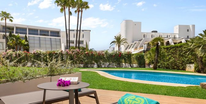 Frau mit Strohhut am Strand vor blauem Meer