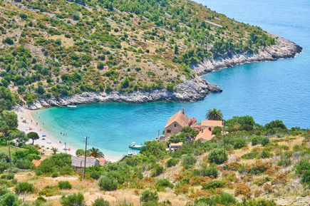Panoramablick auf die Plaža Dubovica auf der Insel Hvar in Kroatien mit geschützter Kiesbucht, kristallklarem Meer, traditionellen Steinhäusern und mediterraner Vegetation