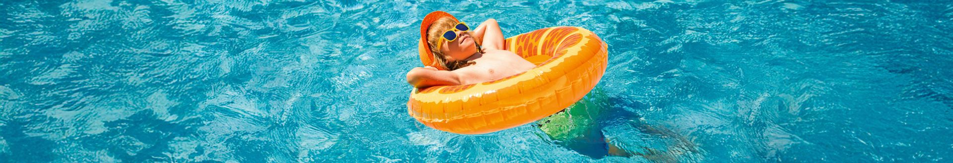 Kind entspannt im orangefarbenen Schwimmreifen im Pool und treibt im klaren, blauen Wasser