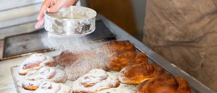 Frisch gebackene Ensaimadas, mit Puderzucker bestreut, auf einem Backblech