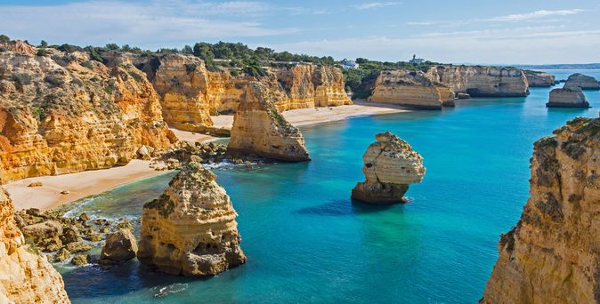 Küste der Algarve mit markanten Felsformationen und klarem blauem Wasser unter bewölktem Himmel