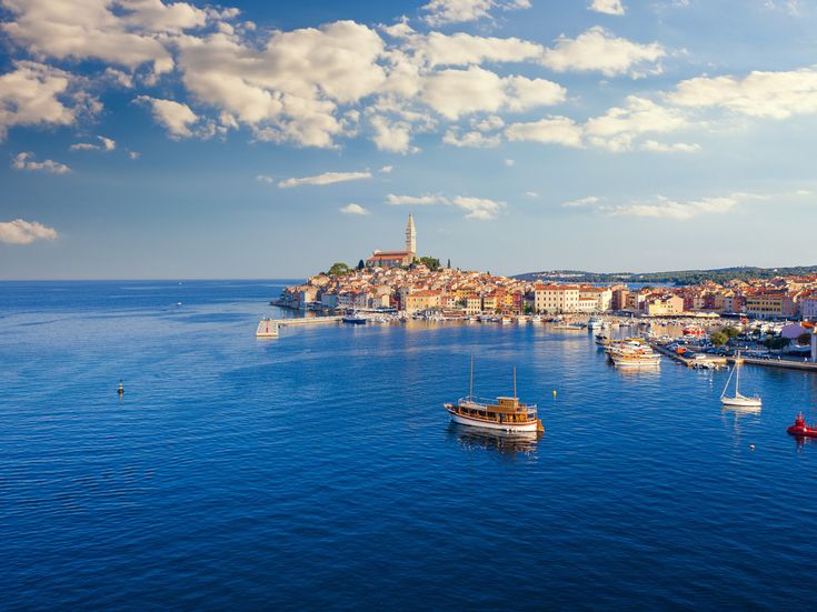 Hafen und Altstadt von Rovinj in Istrien, Kroatien, mit Kirche auf Hügel, Booten im Adriatischen Meer und historischer Küstenstadt