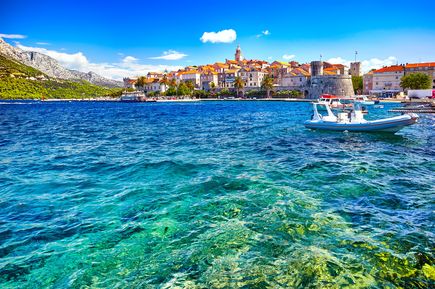 Blick auf die historische Altstadt von Korčula in Kroatien mit Stadtmauer, Hafen, Booten und kristallklarem Adriatischen Meer vor der Küste der Insel Korčula