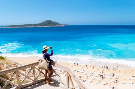 Aussicht auf den Kaputaş Beach mit hellem Sand, intensiv blauem Meer und Badegästen, eingerahmt von Felsen und Natur