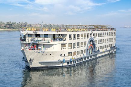 MS Lady Carol, großes weißes Nilkreuzfahrtschiff mit mehreren Decks, fährt auf dem Nil, Ufer mit Palmen im Hintergrund