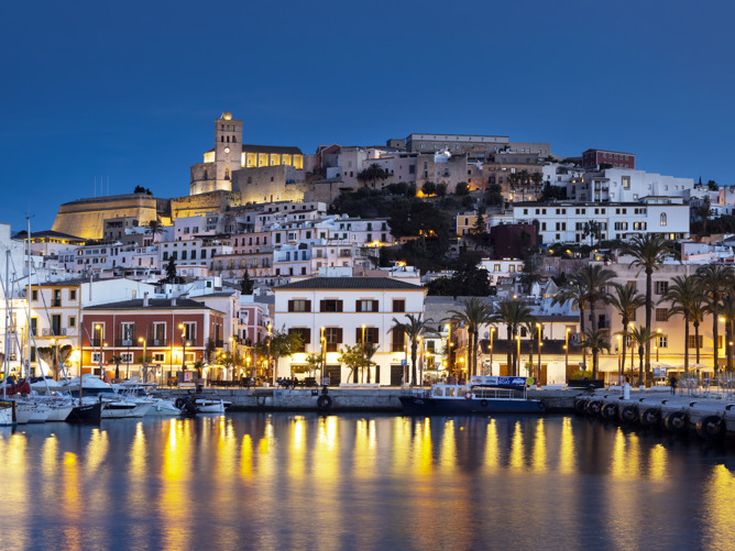 Abendstimmung im Hafen von Ibiza-Stadt mit beleuchteter Altstadt und spiegelnden Lichtern im Wasser
