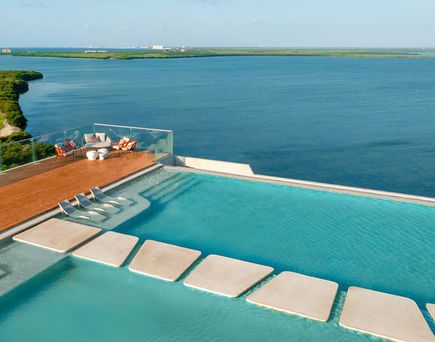 Rooftop-Pool des Hyatt Vivid Grand Island in Cancún, Mexiko. Pool mit flachen Steinen, Liegen und Blick auf das Wasser.