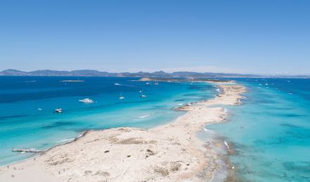 Luftaufnahme des Playa de ses Illetes auf Formentera mit feinem weißen Sand, türkisblauem Meer und Yachten im Wasser