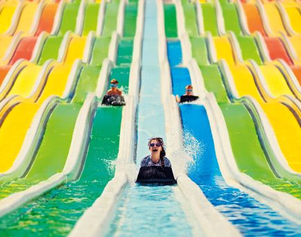 Kinder rutschen auf bunten Wasserrutschen mit Matten in einem Aquapark