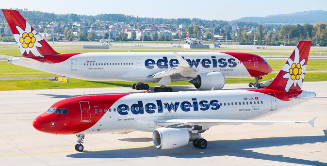 Zwei Edelweiss-Passagierflugzeuge auf einem Rollfeld nebeneinander mit Berglandschaft im Hintergrund