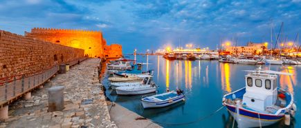 Alter Hafen von Heraklion mit der venezianischen Festung Koules, Booten und Jachthafen während der blauen Stunde, Kreta, Griechenland. Boote verschwimmen im Vordergrund.