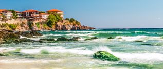 Küstenabschnitt von Sosopol in Bulgarien mit historischen Gebäuden auf Felsen über dem Schwarzen Meer und Wellen an der Küste