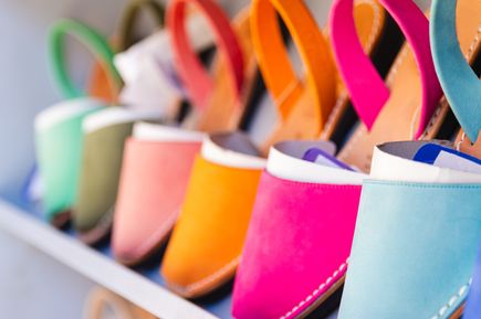 Mehrere bunte Lederschuhe stehen nebeneinander in einer Reihe und präsentieren kräftige Farben wie Pink, Orange und Türkis