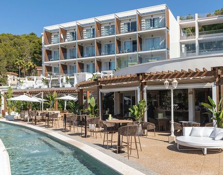 Moderner Terrassenbereich des Valentin Grand Park mit Outdoor-Restaurant, Lounge-Möbeln und schmalem Poolkanal vor dem Gebäude unter blauem Himmel