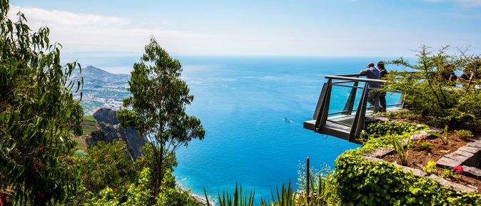 Besucher auf der Aussichtsplattform Cabo Girão auf Madeira mit Blick über die Steilküste, den Atlantik, grüne Terrassenlandschaften und die Küste der Insel