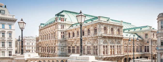 Historisches Gebäude der Wiener Staatsoper mit klassischer Architektur und grünen Dächern, aufgenommen bei klarem Himmel