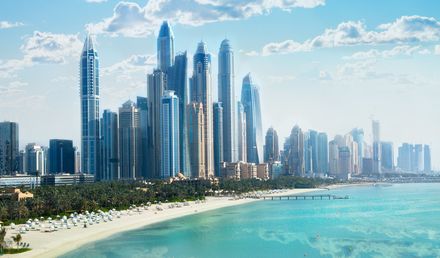 Blick auf die Dubai Marina mit zahlreichen modernen Wolkenkratzern entlang der Küste und einem hellen Sandstrand am türkisfarbenen Wasser
