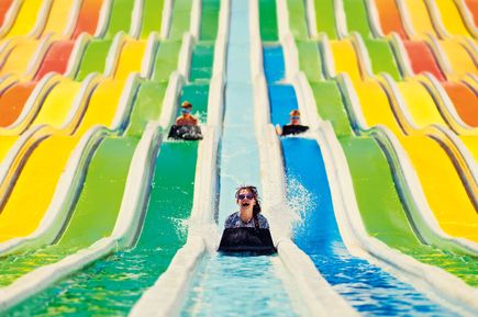 Kinder rutschen auf bunten Wasserrutschen mit Matten in einem Aquapark