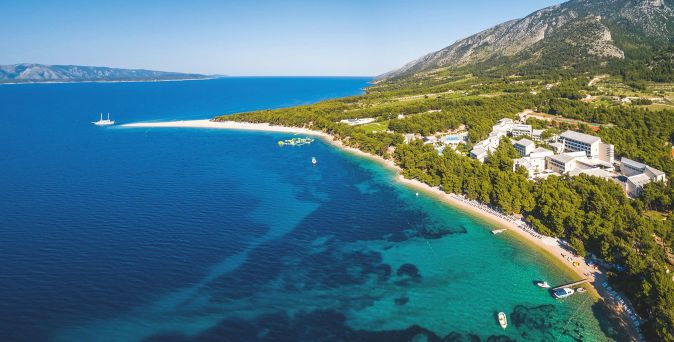 Luftaufnahme des Bretanide Sport & Wellness Resorts an der kroatischen Küste mit Strand, Pinienwald und Bergen im Hintergrund