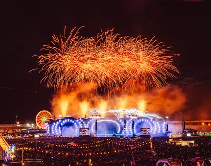 Feuerwerk über der beleuchteten Hauptbühne des Glücksgefühle Festivals vor großer Menschenmenge bei Nacht.