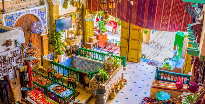 Innenhof eines traditionellen tunesischen Hauses mit bunten Fliesen, hölzernen Möbeln und dekorativen Lampen